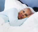 Closeup of a woman lying on her side while in bed.